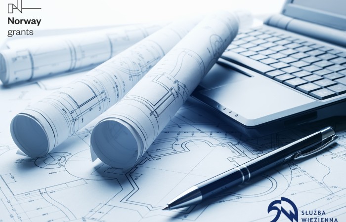 In the photo, white architectural drawings. Next to them a laptop and a pen. 