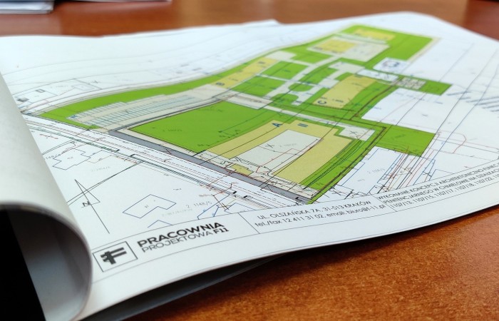 Building’s architectural plan on the brown-topped table. Green indications in the picture. Building’s architectural plan on the brown-topped table. Green indications in the picture.