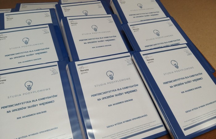 Students' binders with white covers inside lying on the brown-top table. Students' binders with white covers inside lying on the brown-top table.