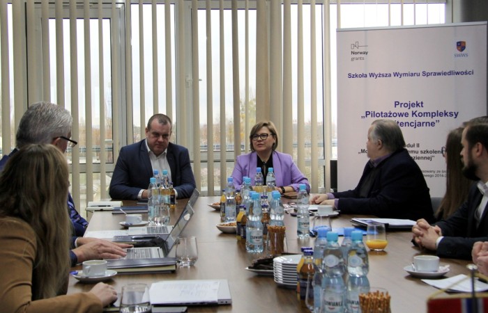 Grupa ludzi prowadzi dyskusję przy stole konferencyjnym. Spoglądają w kierunku osób przemawiających. Na stole notatniki, laptopy, woda i poczęstunek dla gości. Grupa ludzi prowadzi dyskusję przy stole konferencyjnym. Spoglądają w kierunku osób przemawiających. Na stole notatniki, laptopy, woda i poczęstunek dla gości.