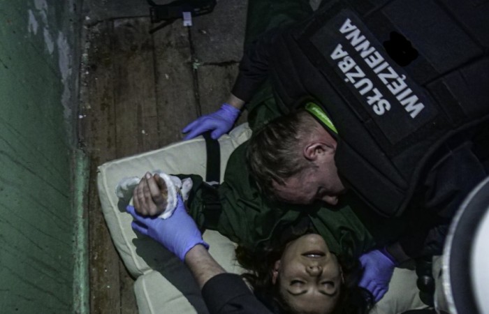 Funkcjonariusz Służby Więziennej pochyla się nad osobą poszkodowaną w wypadku, w celu oceny jej stanu i udzielenia pomocy. Funkcjonariusz Służby Więziennej pochyla się nad osobą poszkodowaną w wypadku, w celu oceny jej stanu i udzielenia pomocy.