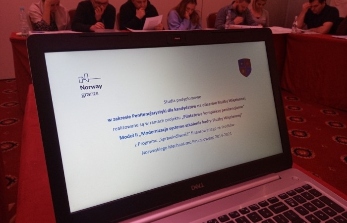 Na pierwszym planie zdjęcia włączony laptop z informacją dotyczącą projektu, godłem uczelni i logo NMF. Na drugim planie grupa osób pochylona nad notatkami. Na pierwszym planie zdjęcia włączony laptop z informacją dotyczącą projektu, godłem uczelni i logo NMF. Na drugim planie grupa osób pochylona nad notatkami.