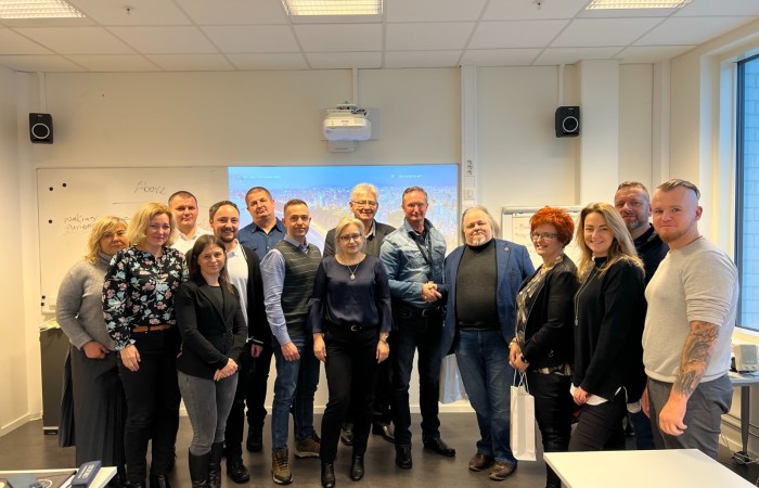 Uczestnicy spotkania w Norwegii pozują do wspólnego zdjęcia na tle ściany pokoju wykładowego. Za nimi obraz z rzutnika multimedialnego. Uczestnicy spotkania w Norwegii pozują do wspólnego zdjęcia na tle ściany pokoju wykładowego. Za nimi obraz z rzutnika multimedialnego.